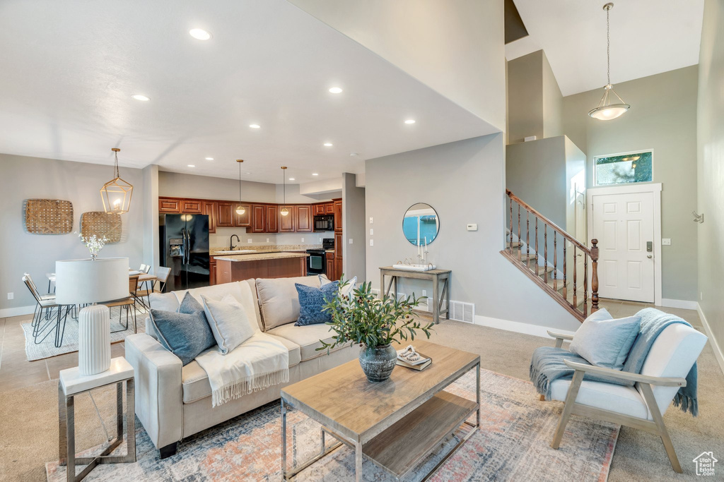 Living area with stairway, recessed lighting, a high ceiling, and light carpet