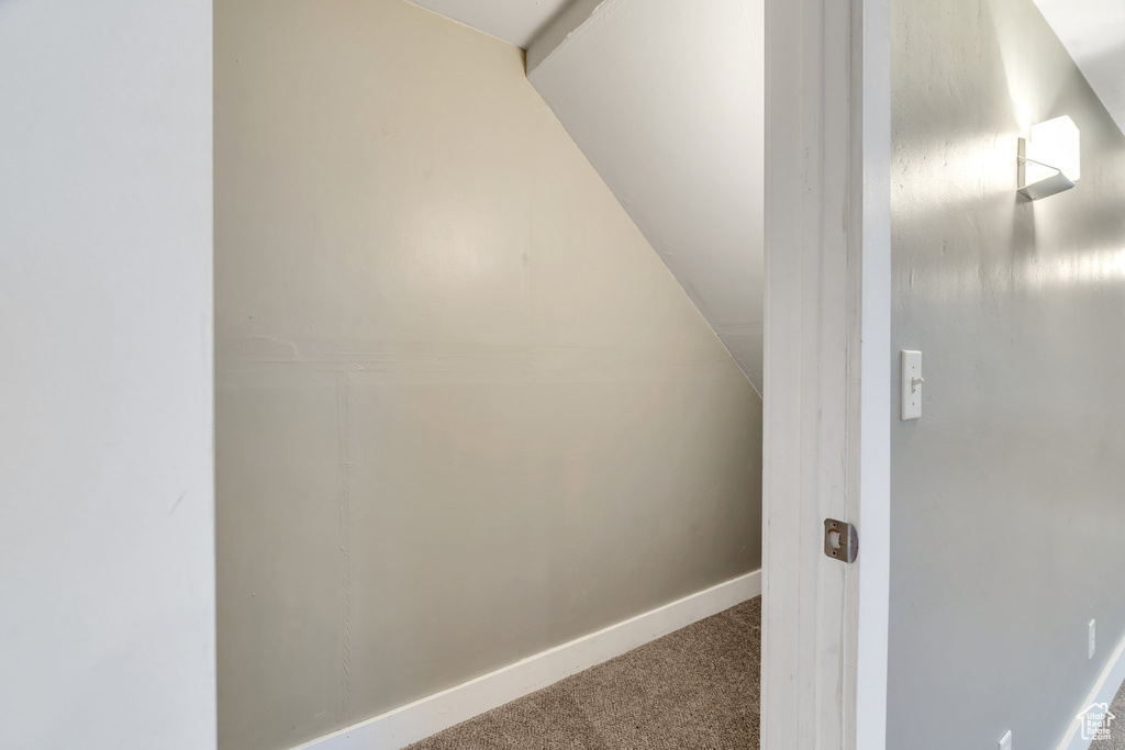 Interior space with carpet flooring and lofted ceiling