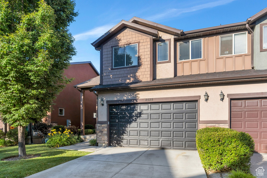 View of front of home with an attached garage, driveway, board and batten siding, and stucco siding