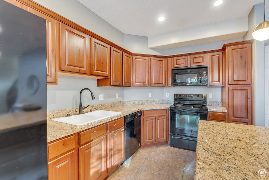 Kitchen with black appliances, light tile patterned flooring, recessed lighting, brown cabinetry, and decorative light fixtures