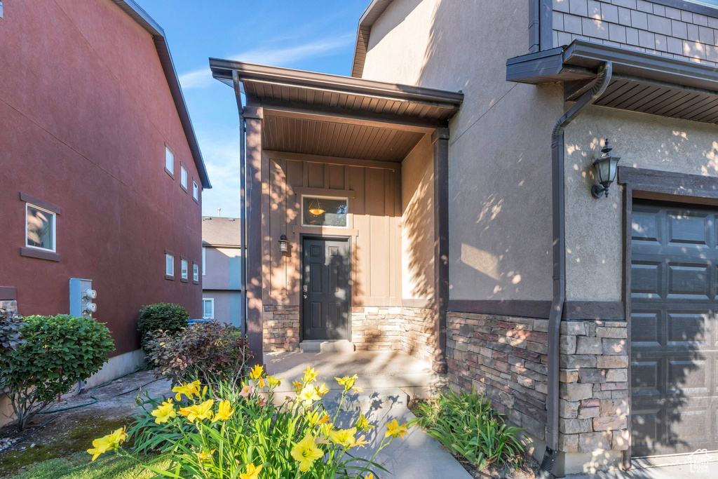 Property entrance with a garage, stone siding, and stucco siding