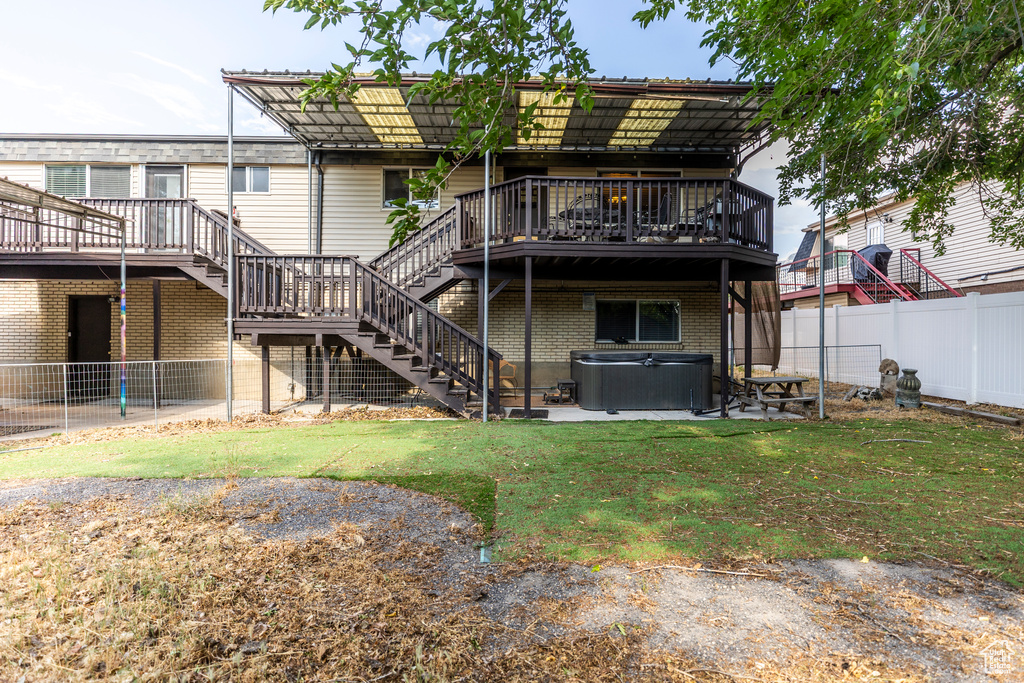 Back of house with a hot tub, stairs, a deck, a fenced backyard, and brick siding
