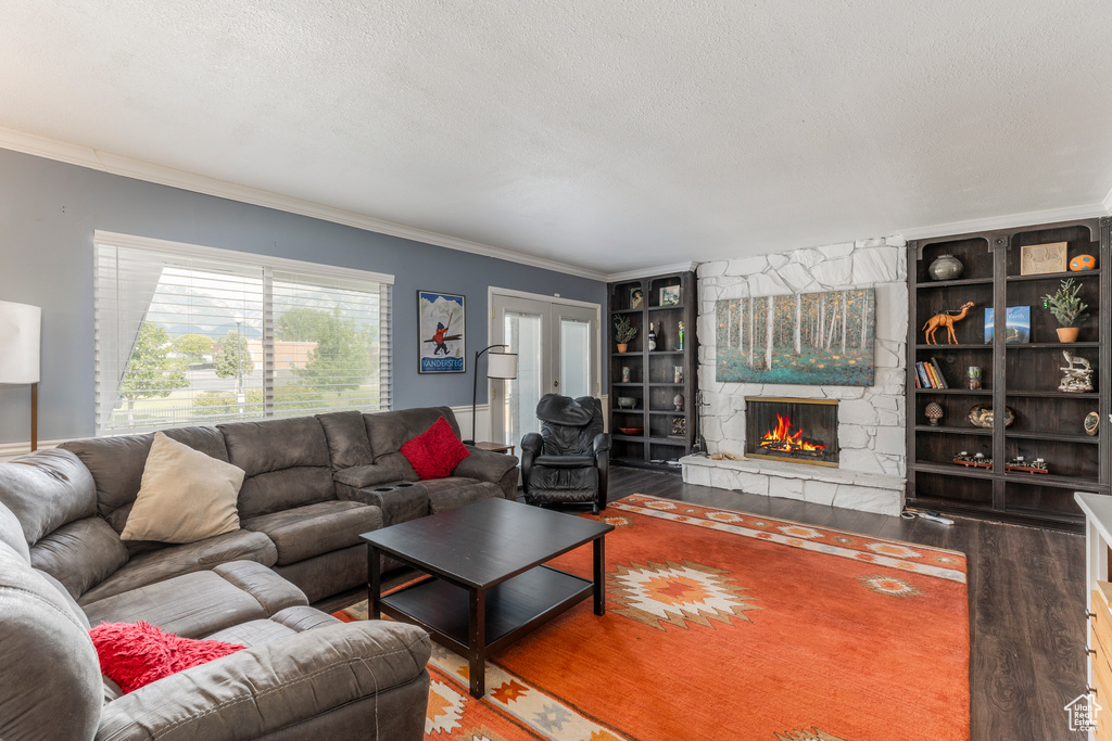 Living area with wood finished floors, ornamental molding, a textured ceiling, built in features, and a fireplace