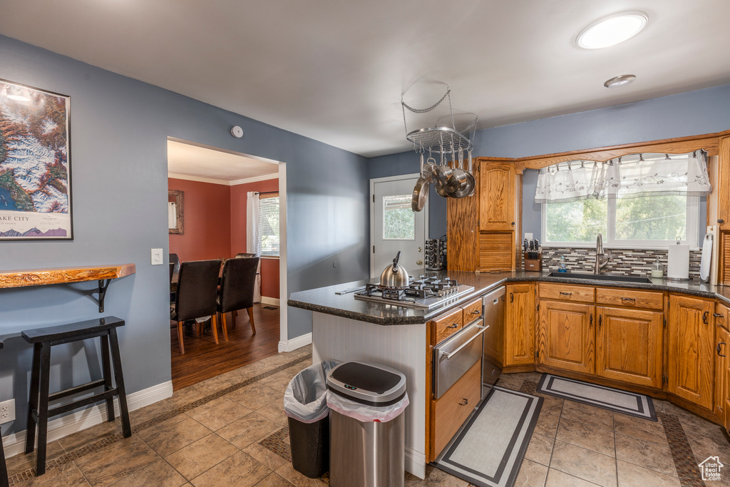 Kitchen featuring stainless steel appliances, a warming drawer, a peninsula, brown cabinetry, and decorative backsplash