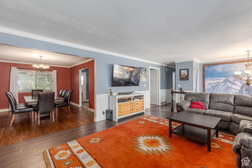 Living room with a chandelier, ornamental molding, and dark wood finished floors