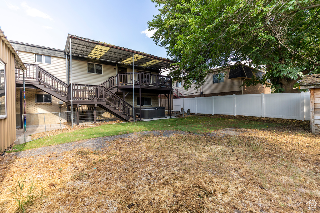 Back of house featuring a hot tub, stairs, a fenced backyard, and a wooden deck