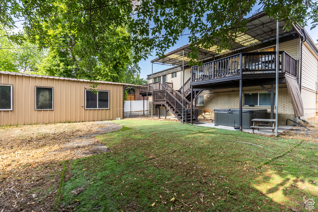 View of yard featuring a hot tub, a deck, stairs, and a patio area