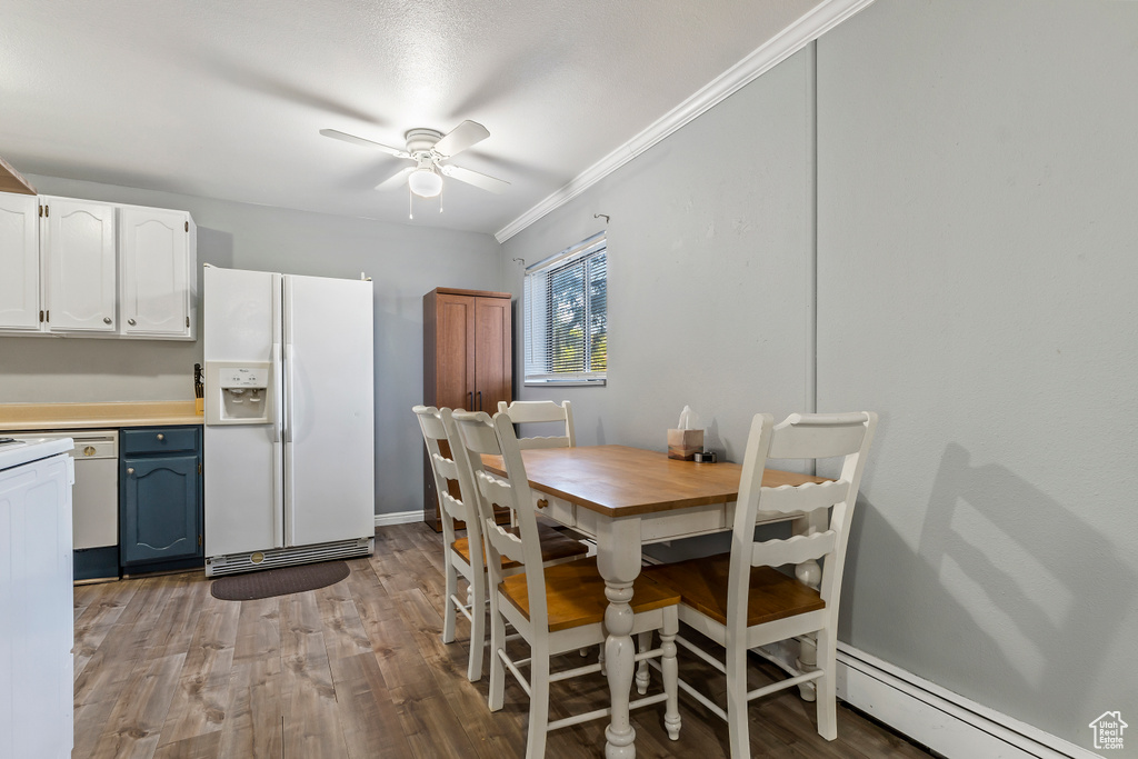 Dining space with a baseboard heating unit, ceiling fan, ornamental molding, and wood finished floors