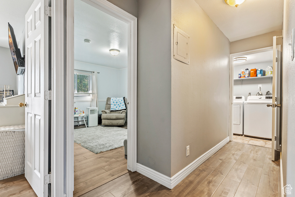 Hall featuring washer and clothes dryer, wood finished floors, and electric panel