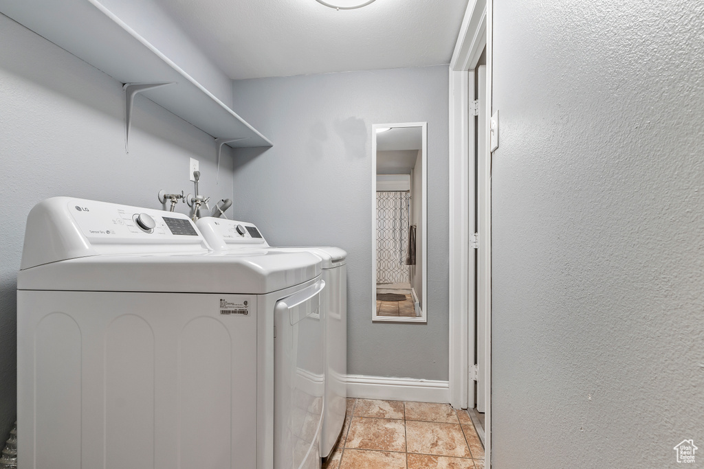 Laundry room featuring independent washer and dryer and light stone finish floors