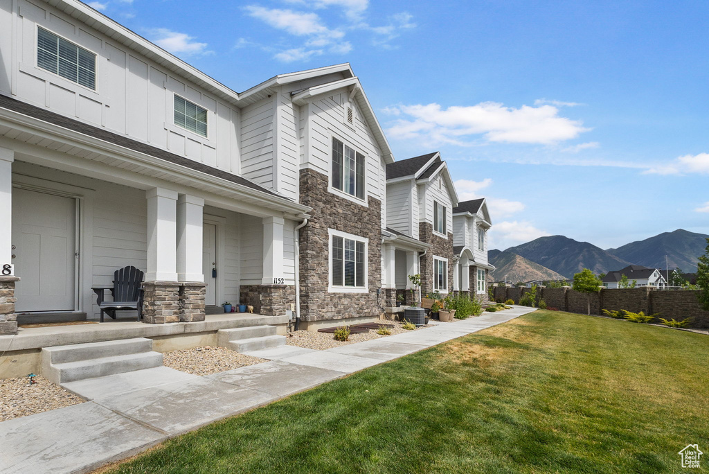 View of front of house featuring stone siding, a porch, a mountain view, a residential view, and board and batten siding