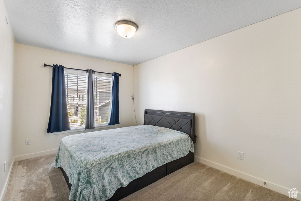 Carpeted bedroom with baseboards and a textured ceiling