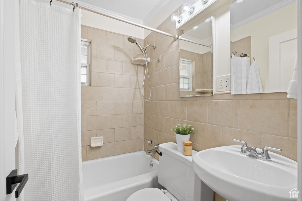 Full bath with crown molding, shower / bathtub combination with curtain, and tile walls