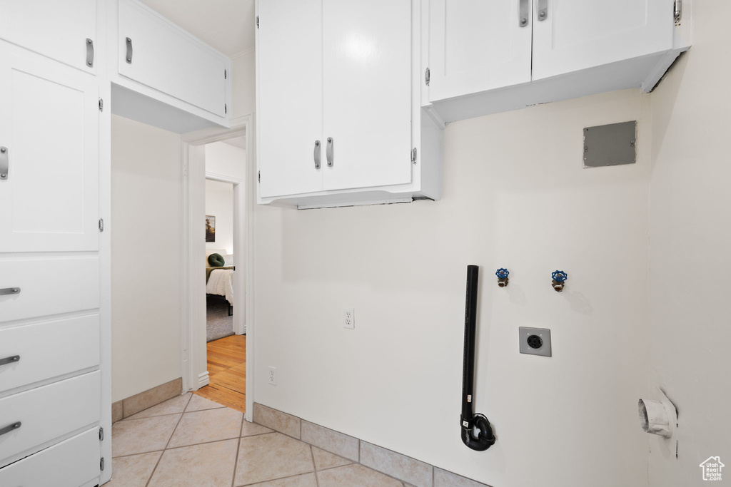 Washroom featuring hookup for an electric dryer, cabinet space, and light tile patterned floors
