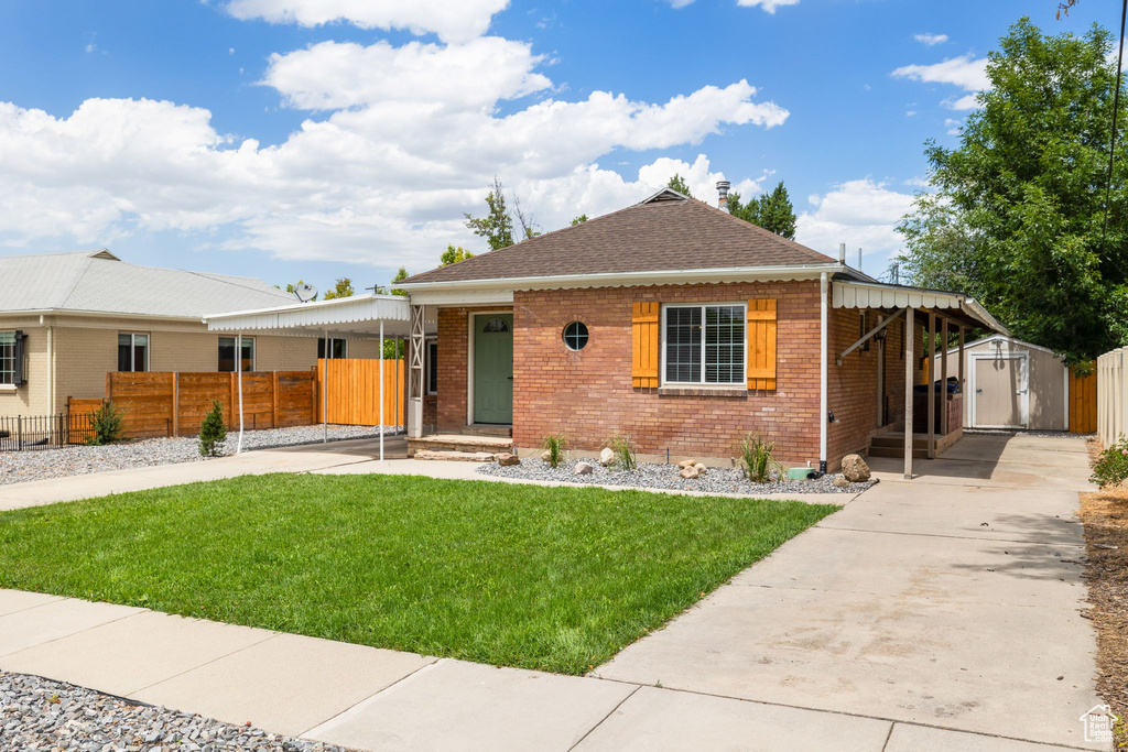 View of front of property with a shed, brick siding, roof with shingles, and concrete driveway