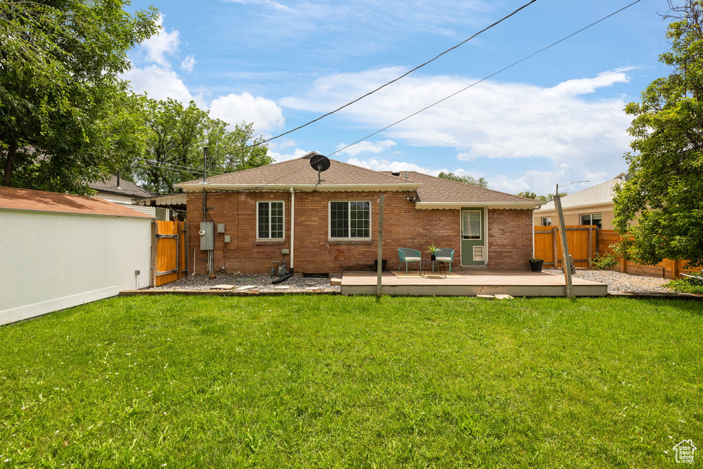 Back of property featuring a deck, a gate, brick siding, and roof with shingles