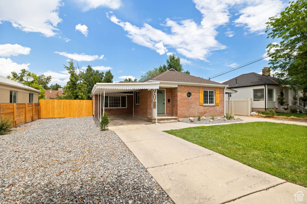 View of front facade with brick siding, an attached carport, and driveway