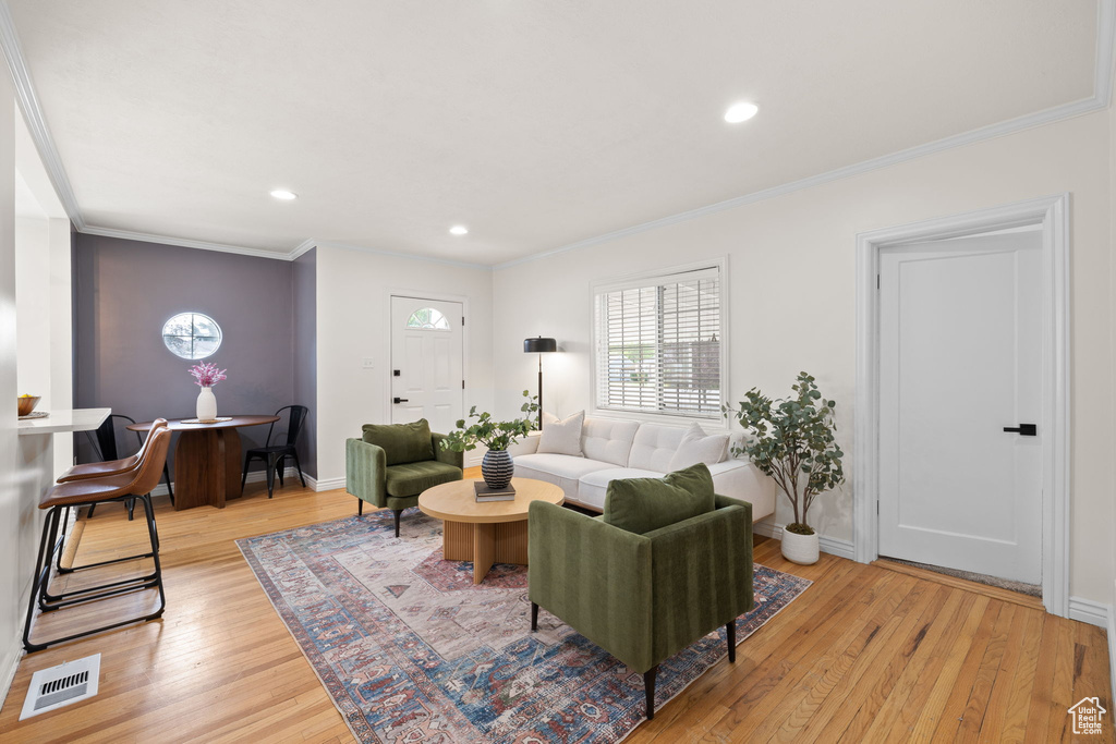 Living room with light wood-style flooring, crown molding, and recessed lighting