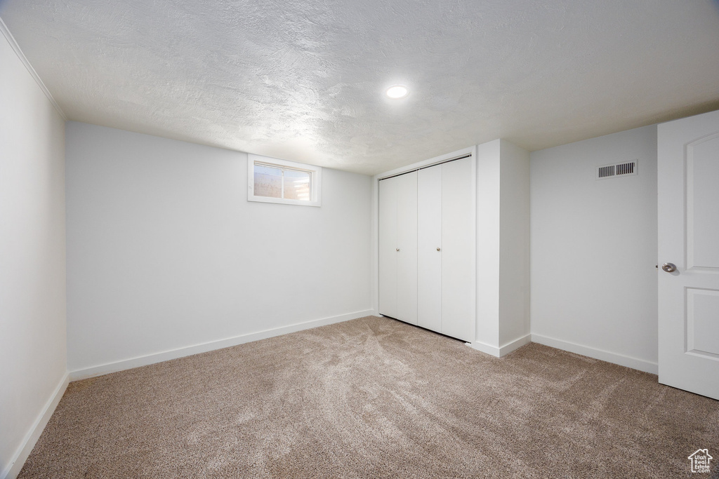 Basement with carpet floors and a textured ceiling