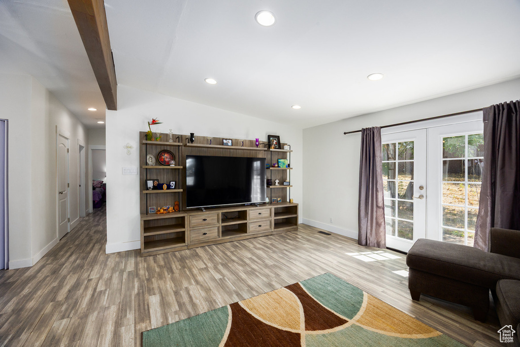 Living area with french doors, wood finished floors, lofted ceiling, and recessed lighting