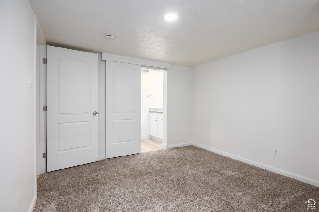 Unfurnished bedroom featuring light carpet and ensuite bath