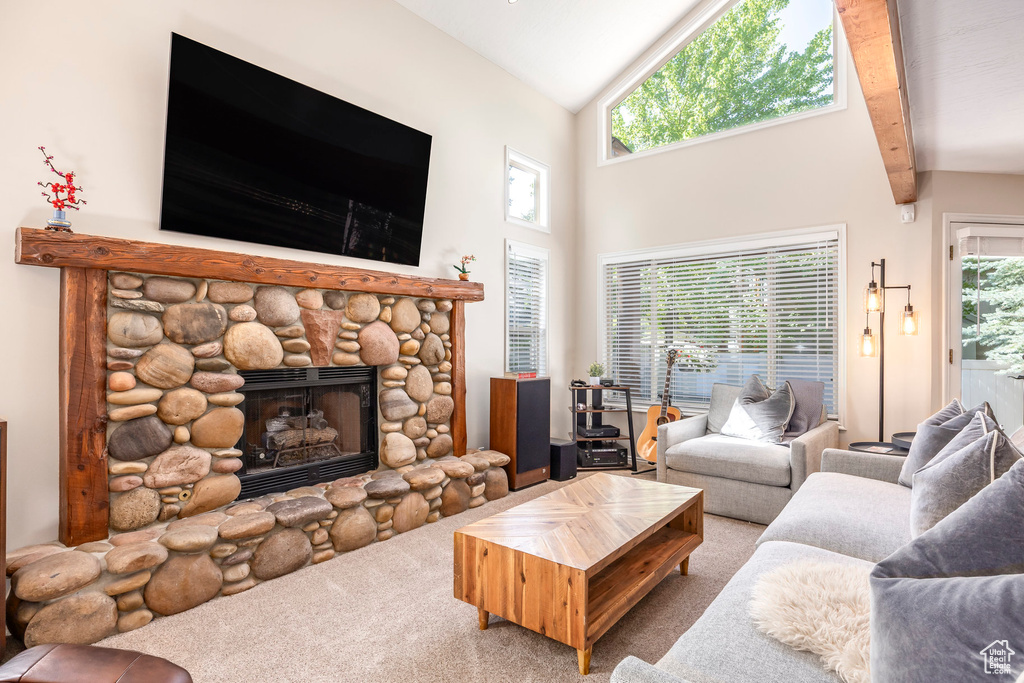 Carpeted living room featuring high vaulted ceiling and a stone fireplace