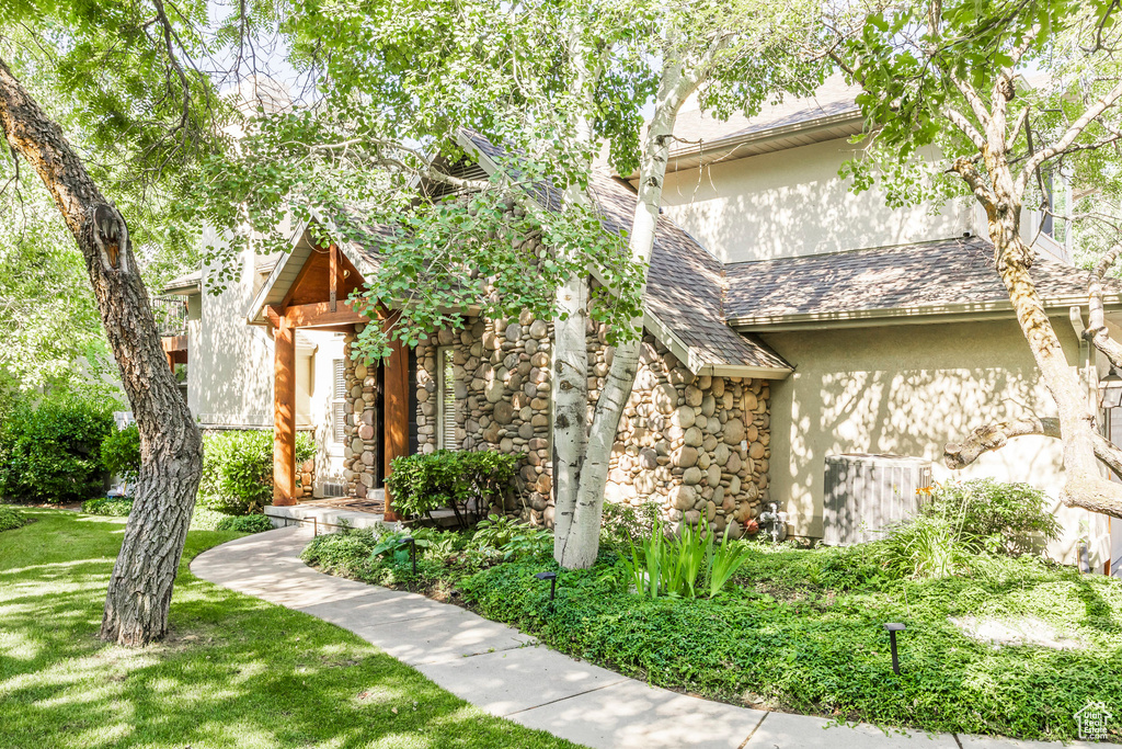 View of front of home with stucco siding, stone siding, and a front yard
