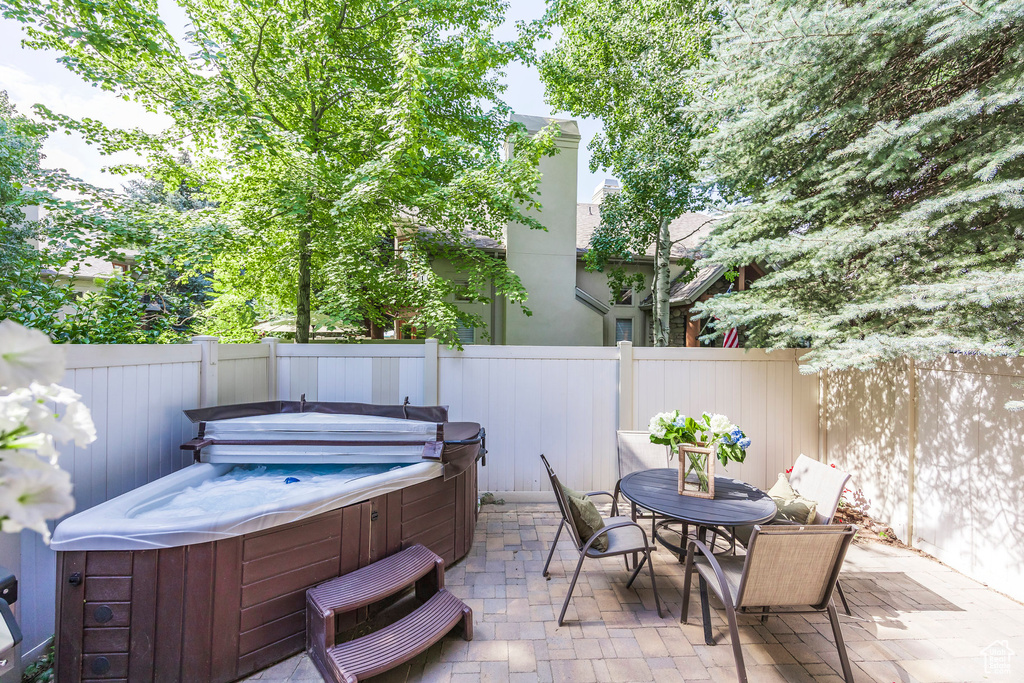 Fenced backyard with a hot tub, a patio area, and outdoor dining space