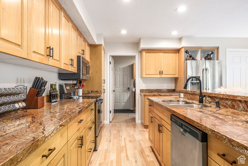 Kitchen with appliances with stainless steel finishes, recessed lighting, light wood finished floors, light brown cabinetry, and dark stone counters