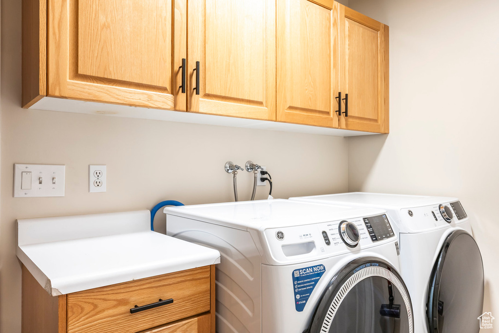 Washroom featuring cabinet space and washer and dryer