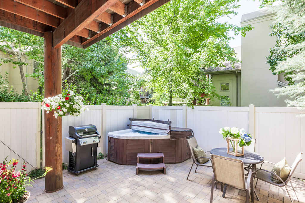Fenced backyard with a hot tub, grilling area, a patio, and outdoor dining area