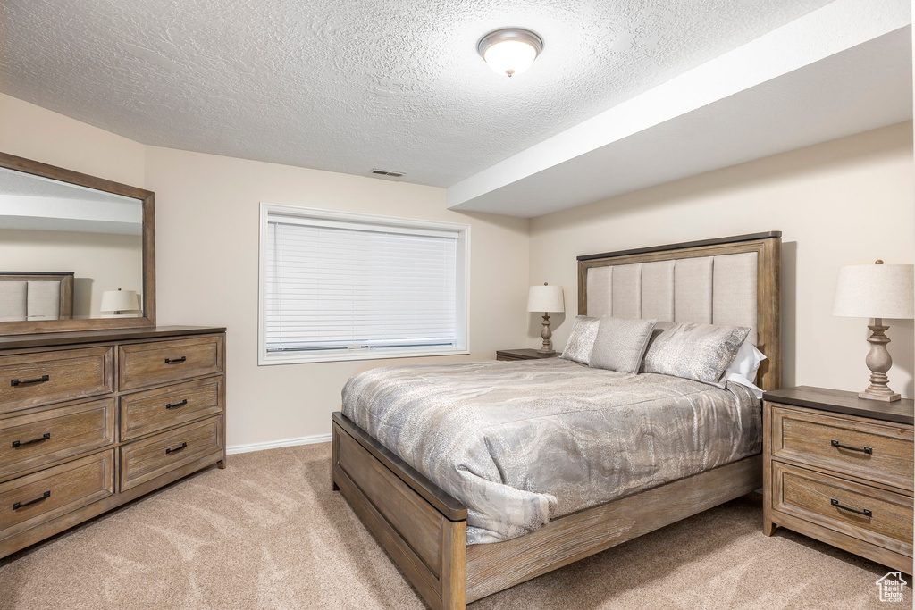 Bedroom with light colored carpet and a textured ceiling