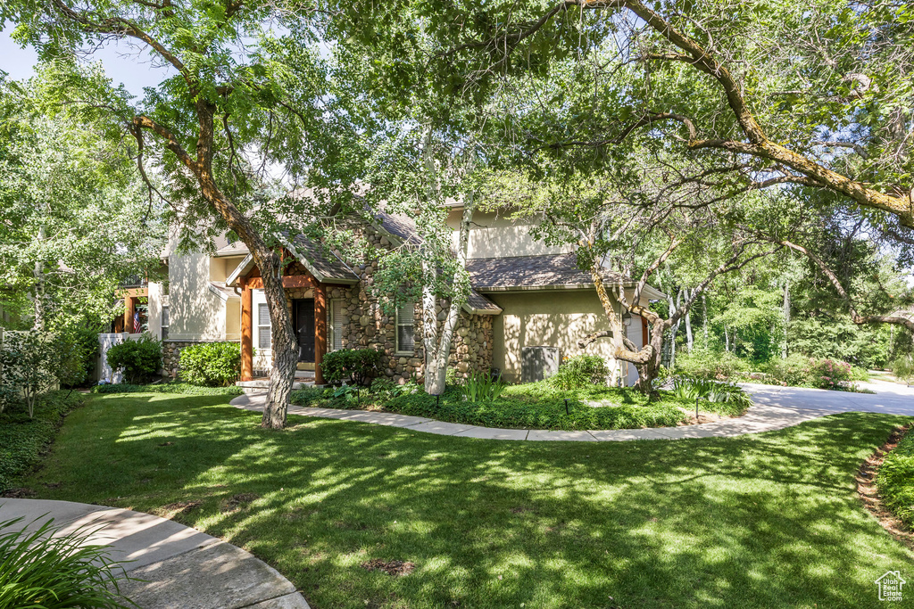View of front of house with stone siding, a front yard, and stucco siding