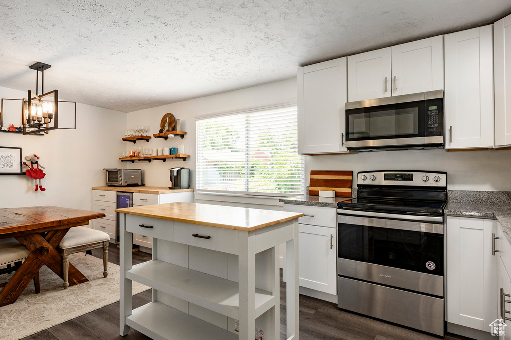 Kitchen with appliances with stainless steel finishes, dark wood-style flooring, a textured ceiling, white cabinetry, and open shelves
