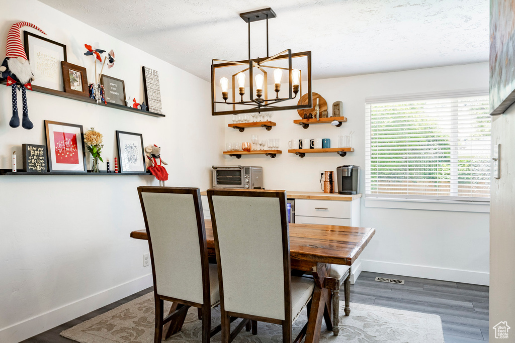 Dining space featuring wood finished floors, a chandelier, and bar area