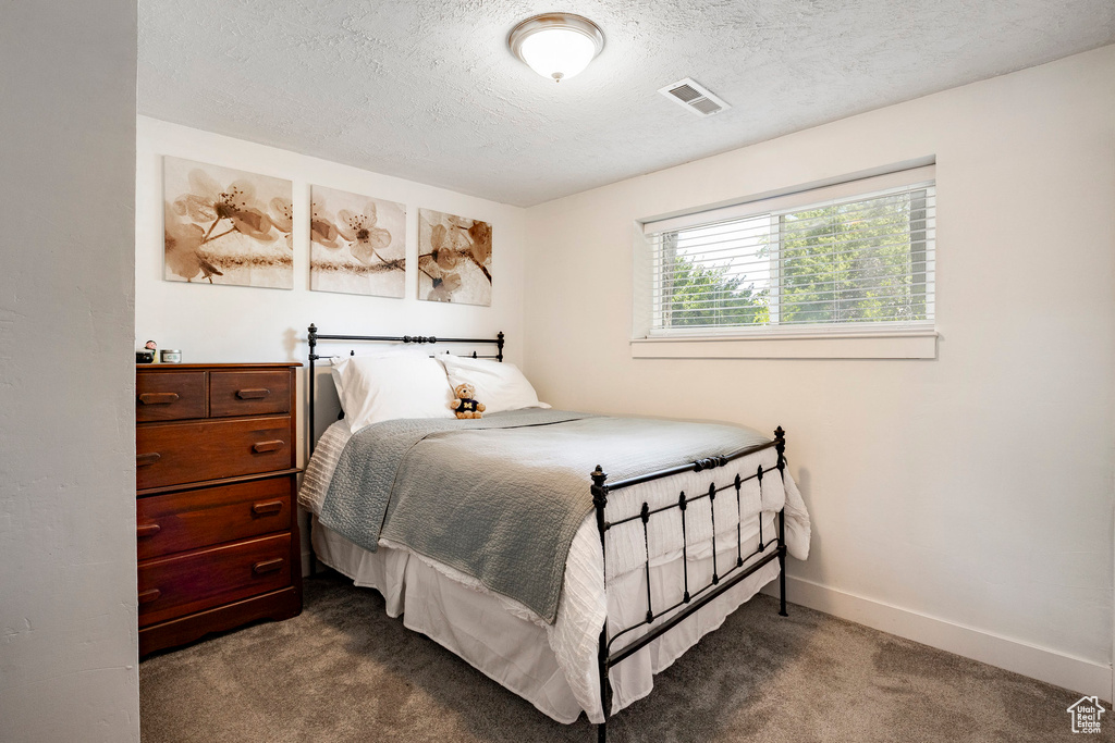 Bedroom with dark colored carpet and a textured ceiling