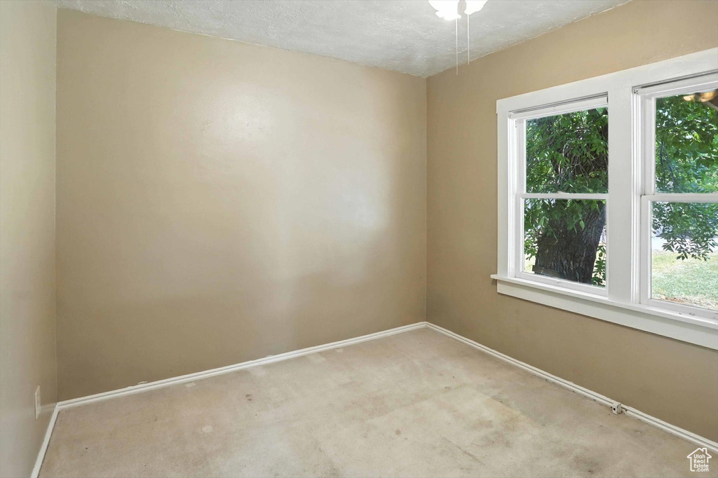 Empty room with light colored carpet and a textured ceiling