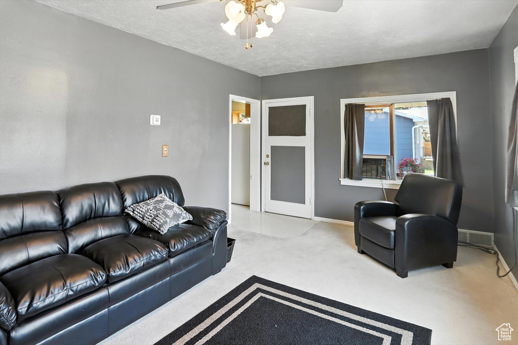 Carpeted living room featuring a ceiling fan and a textured ceiling