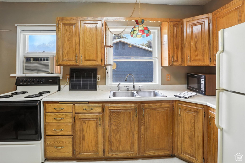 Kitchen featuring white appliances, light countertops, and brown cabinets
