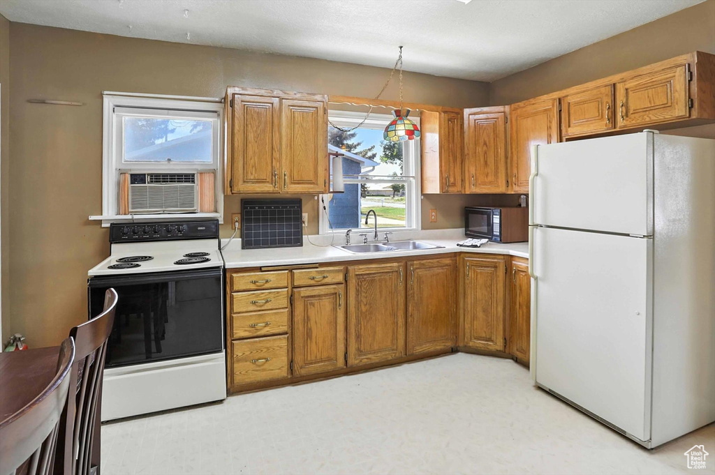 Kitchen featuring white appliances, brown cabinets, light countertops, and a wall mounted air conditioner