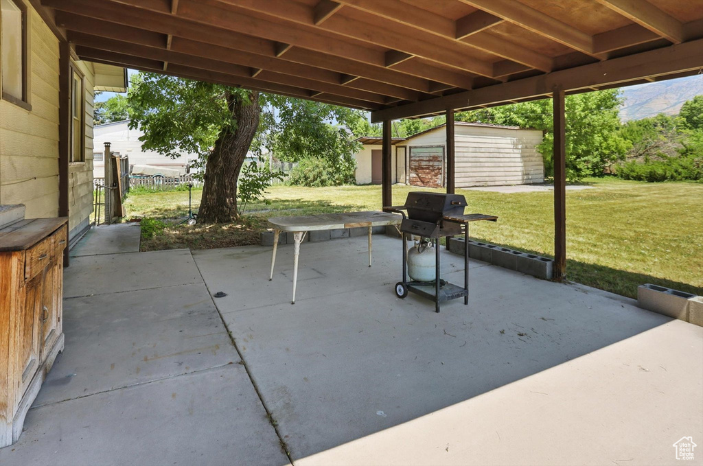 View of patio featuring a storage shed and area for grilling
