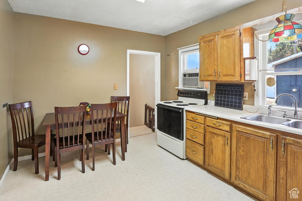 Kitchen featuring white electric range oven, light countertops, and brown cabinets