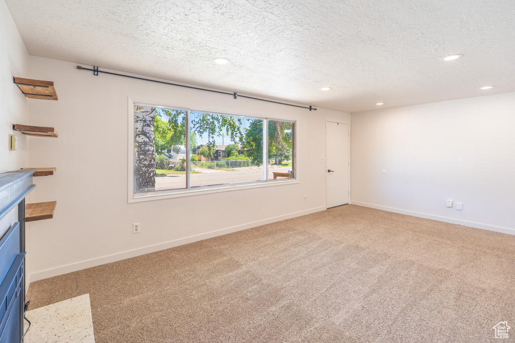 Unfurnished living room featuring light carpet, recessed lighting, and a textured ceiling