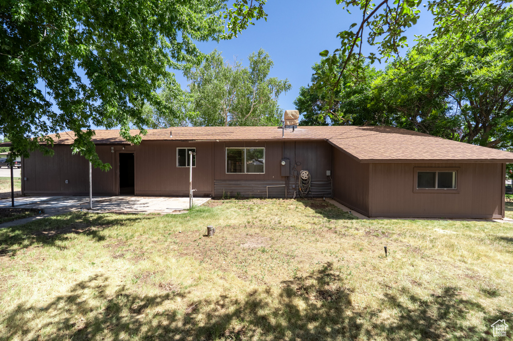 View of front facade with a patio area, a front lawn, and roof with shingles