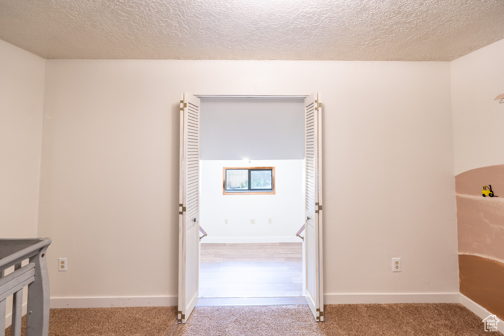 Corridor with a textured ceiling and carpet