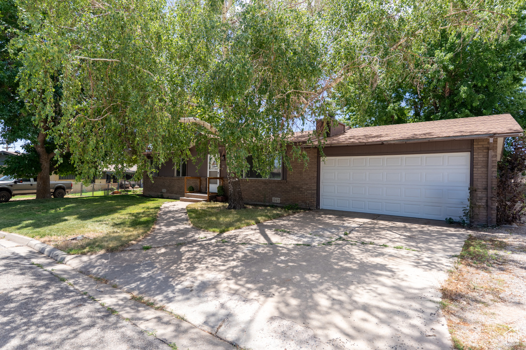 View of front of property featuring brick siding, concrete driveway, a garage, a front yard, and crawl space