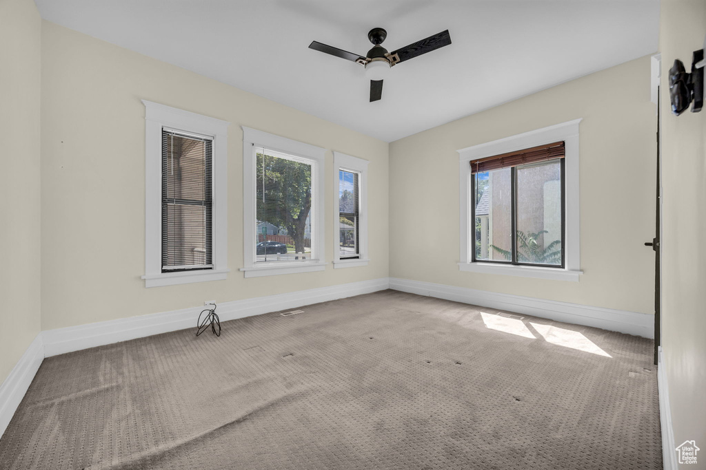 Carpeted spare room with ceiling fan and baseboards
