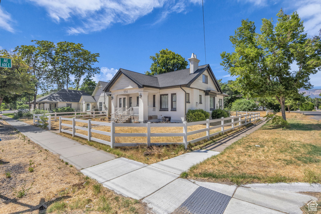 View of front facade featuring a fenced front yard, roof with shingles, and a porch
