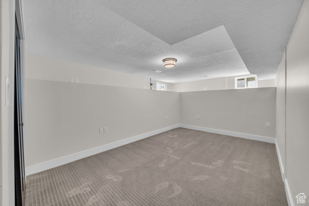 Carpeted empty room with a textured ceiling and healthy amount of natural light