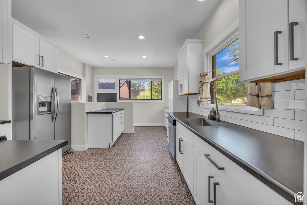 Kitchen featuring appliances with stainless steel finishes, dark countertops, backsplash, recessed lighting, and white cabinetry